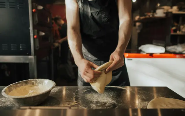 Un homme pétrit de la pâte à Pizza